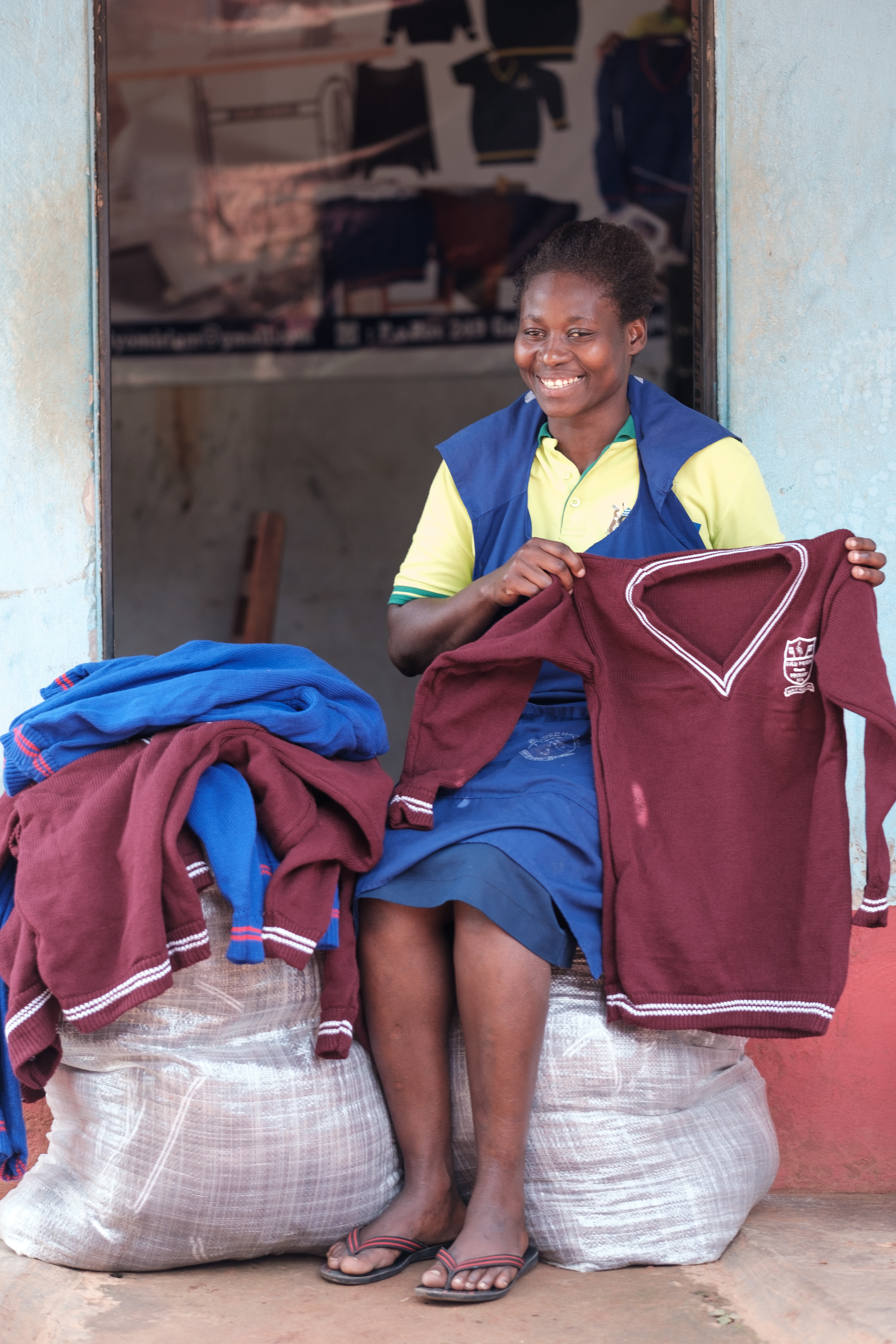 Miriam and some of the school sweaters she made. She is waiting for schools to reopen so that she can deliver them and receive her payment.
